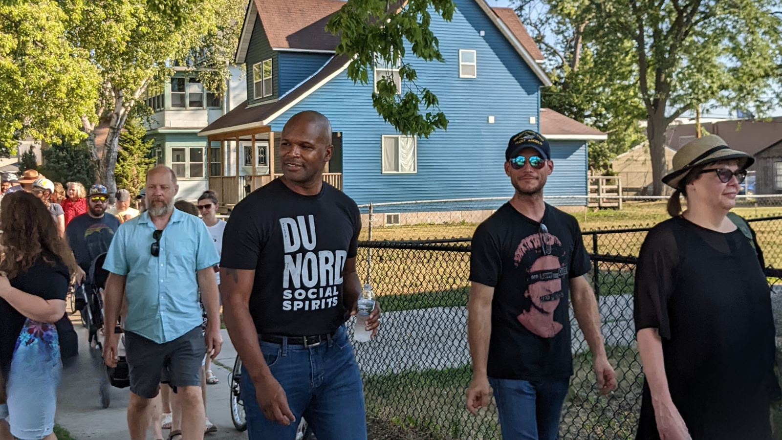 Chris Montana walks in a group of people on a neighborhood street.